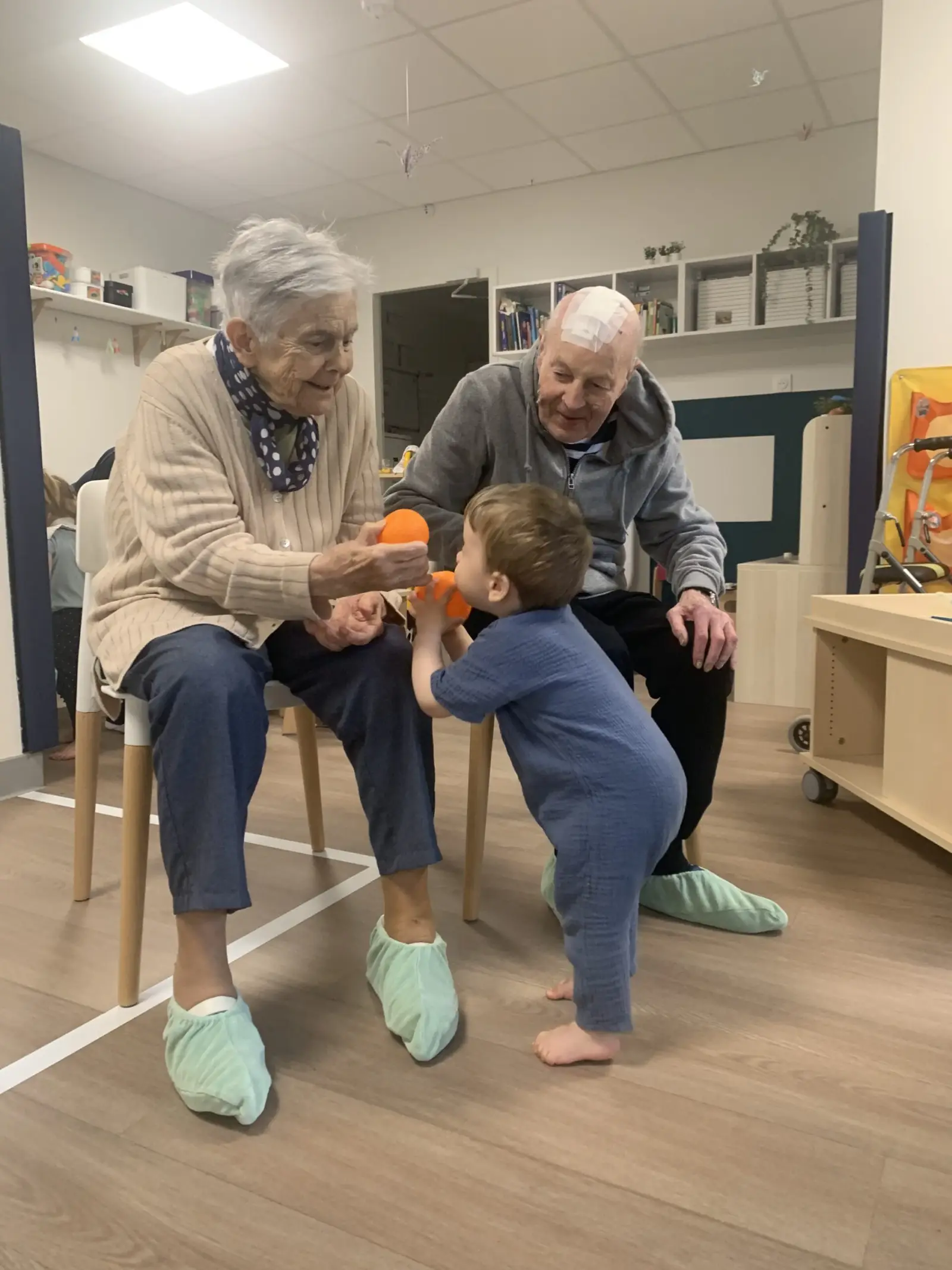 Enfant jouant au ballon avec des résidents de la Rose des Vents à L'Houmeau