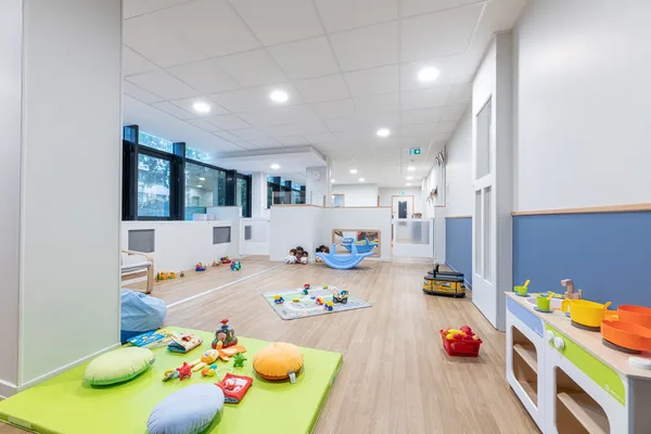 Salle de jeux avec tapis vert et cuisine enfant à la micro-crèche de Convention à Paris 15