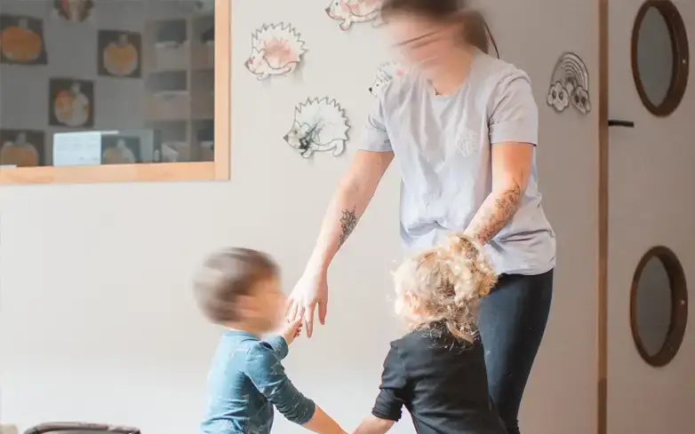Professionnelle jouant avec des enfants dans la salle d'activités de la crèche Bonnetoile