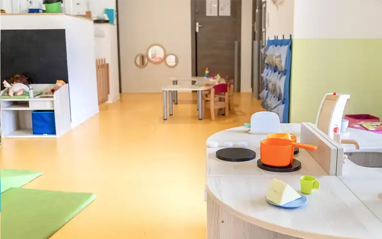 Salle de vie avec coin cuisine dinette et espaces de jeux modulables à la micro-crèche Goupil