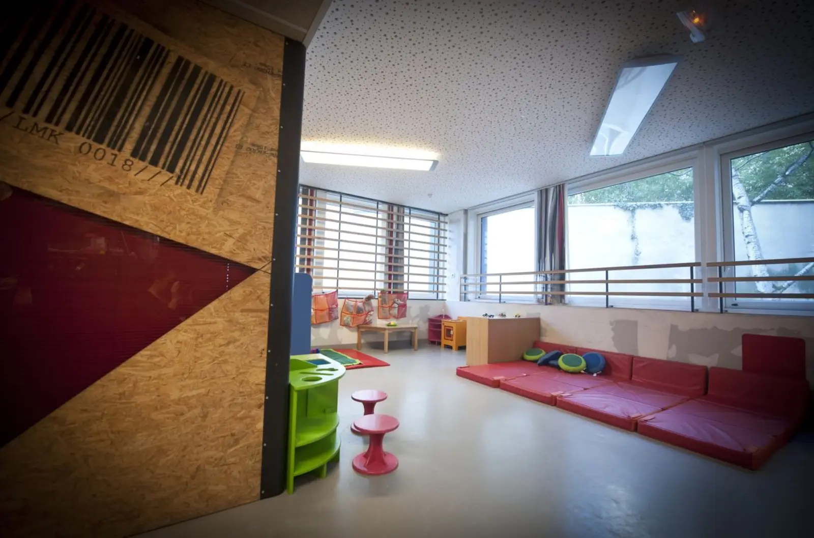 Salle de jeu lumineuse avec baies vitrées à la crèche La Maison Kangourou Picpus
