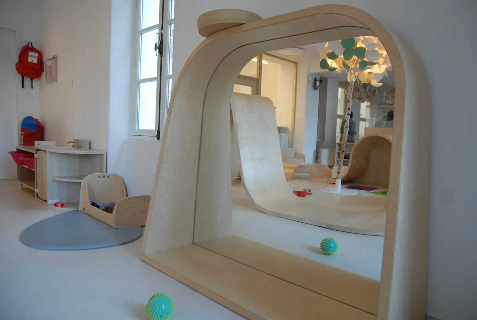 Salle de jeu avec toboggan en bois à la crèche La Maison Kangourou Montparnasse