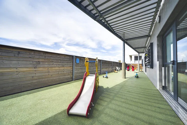 Terrasse extérieure couverte de la crèche Montpellier Parc 2000, toboggan et jeux