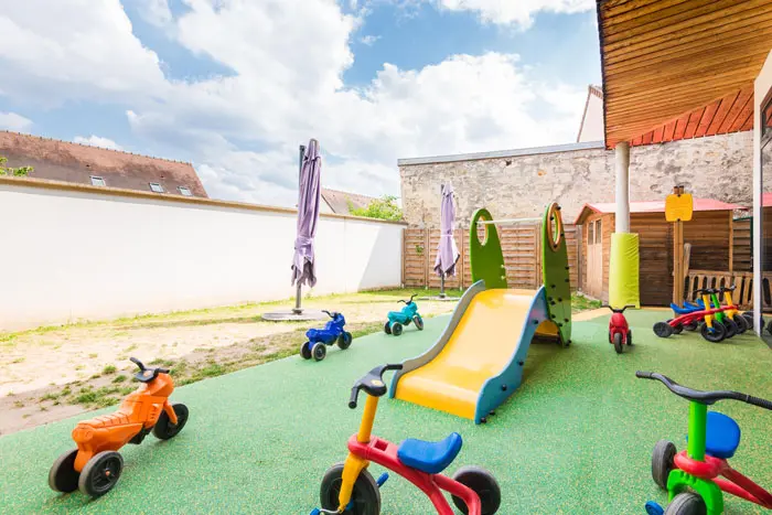 Jardin extérieur de la crèche Croissy avec toboggan et tricycles