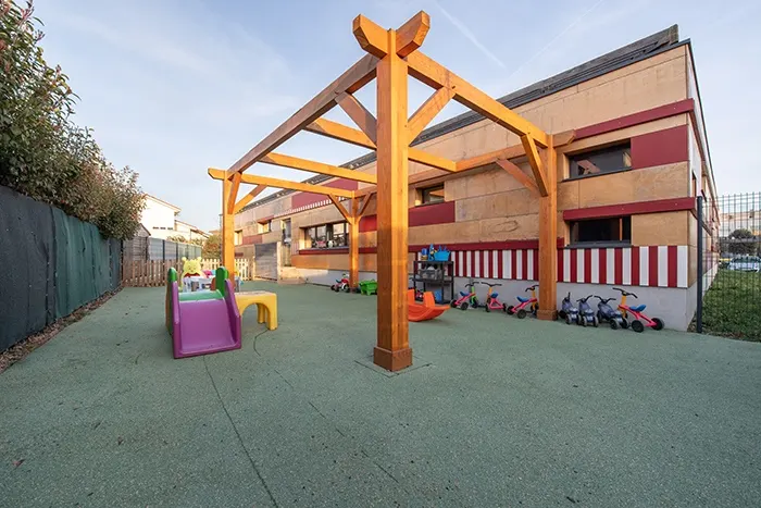 Cour extérieure sous pergola de la crèche Aimargues avec tricycles