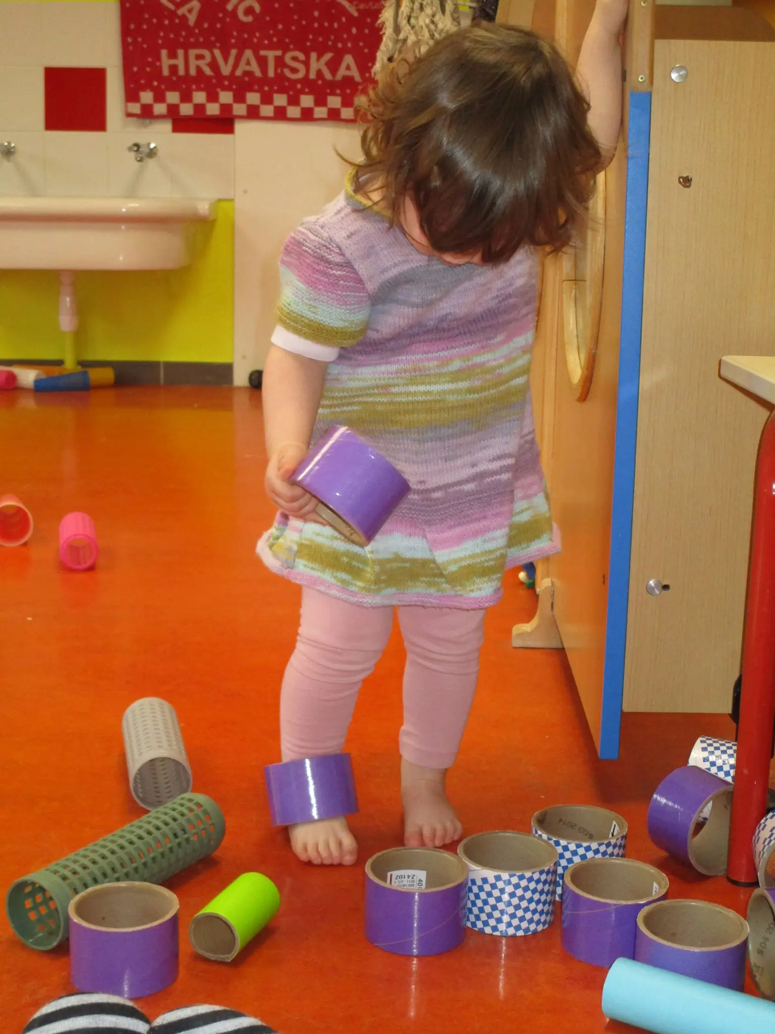 Enfant explorant des rouleaux et tubes colorés à l'Îlot Câlin de Peaugres