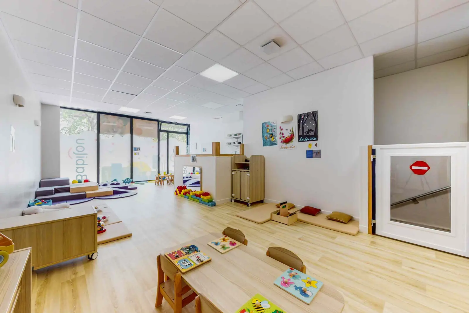 Salle de jeux avec baies vitrées à la micro-crèche Babilou Paris Clouet