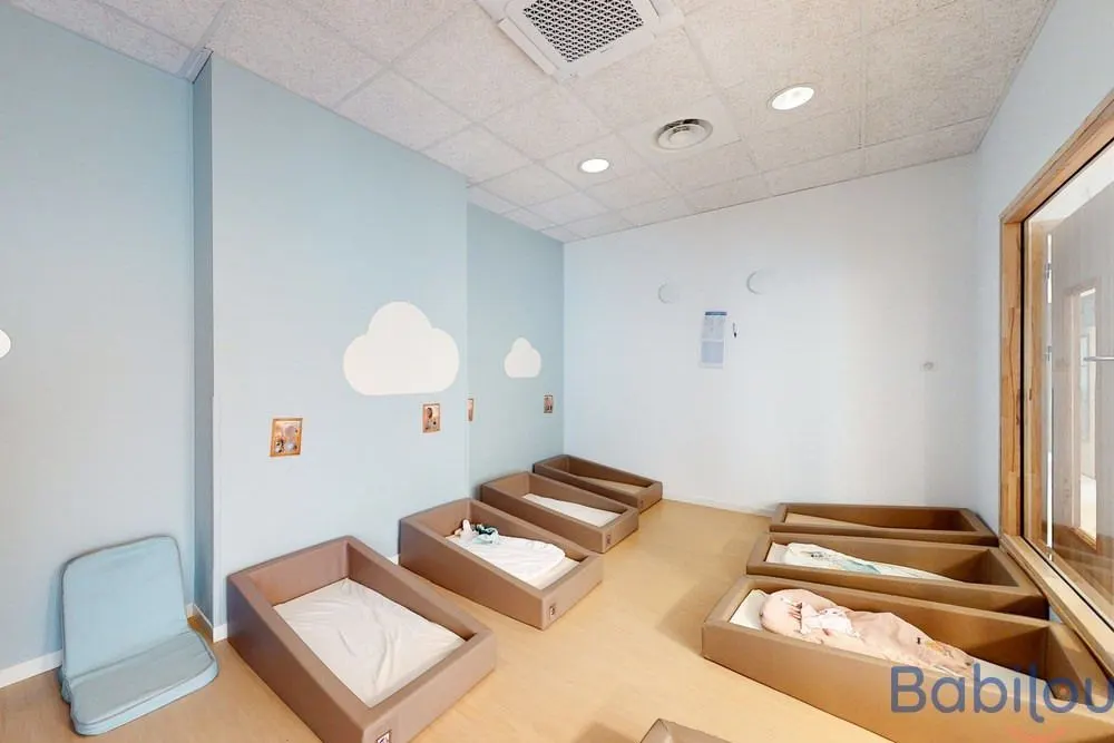 Dortoir aux murs décorés de nuages à la crèche Babilou Clichy Barbusse