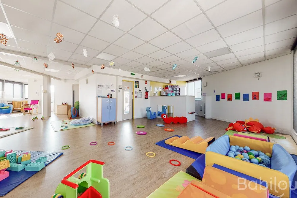 Salle d'éveil avec coin peinture et jeux de motricité à la crèche Babilou Colombes Ecoles