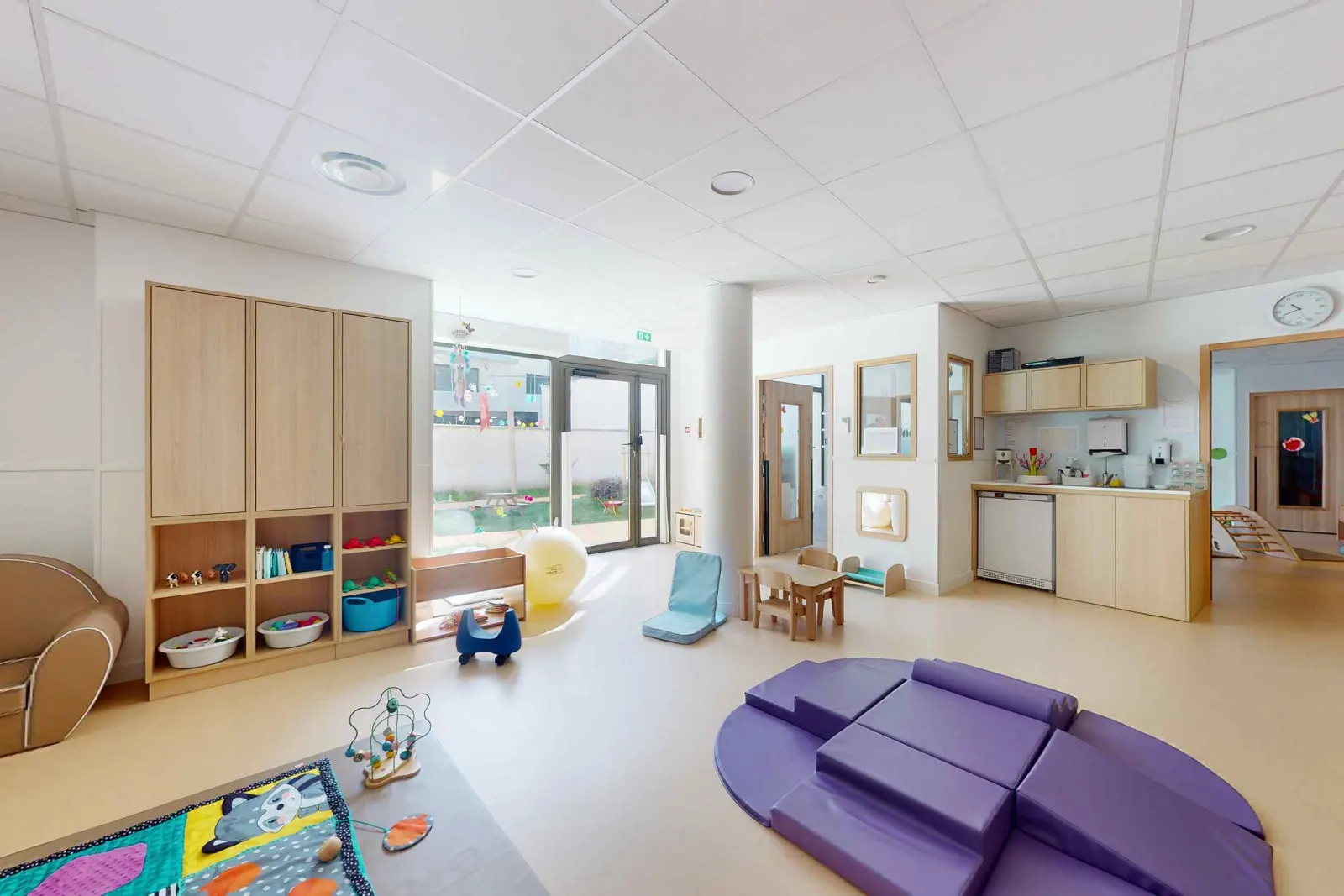 Salle de vie lumineuse avec coin motricité à la crèche Babilou Reims Université