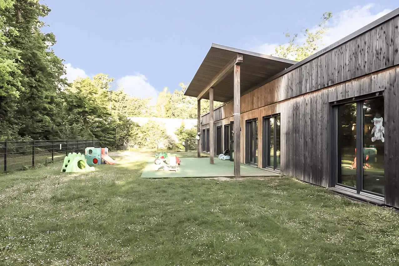 Un bâtiment en bois ouvert sur un grand jardin