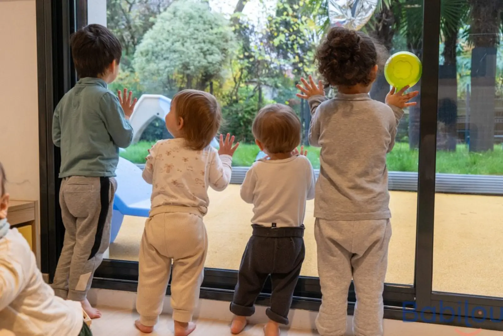 Enfants observant le jardin depuis la baie vitrée de la micro-crèche Babilou Enghien Division Leclerc