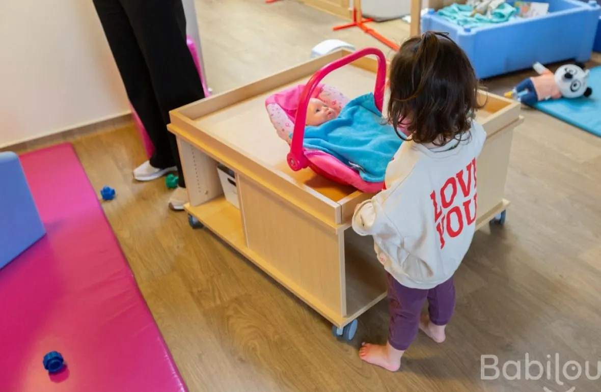 Enfant jouant à l'imitation avec un landau de poupée