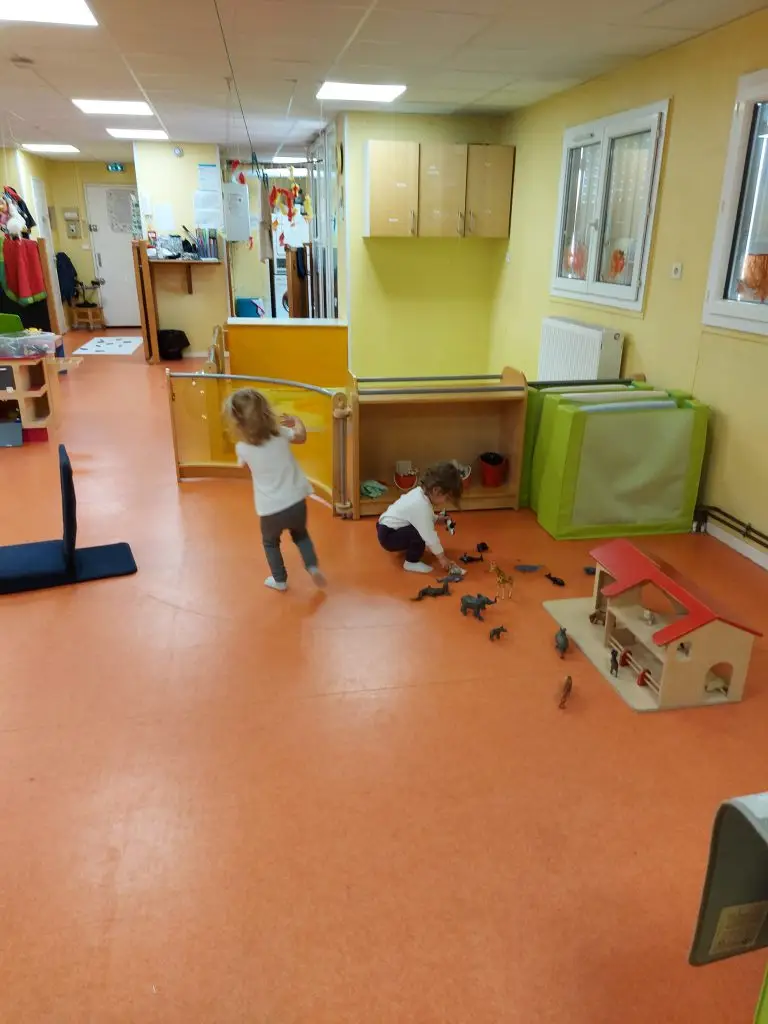 Enfants jouant avec une ferme en bois et des figurines d'animaux à la crèche Petit Némo Villeurbanne