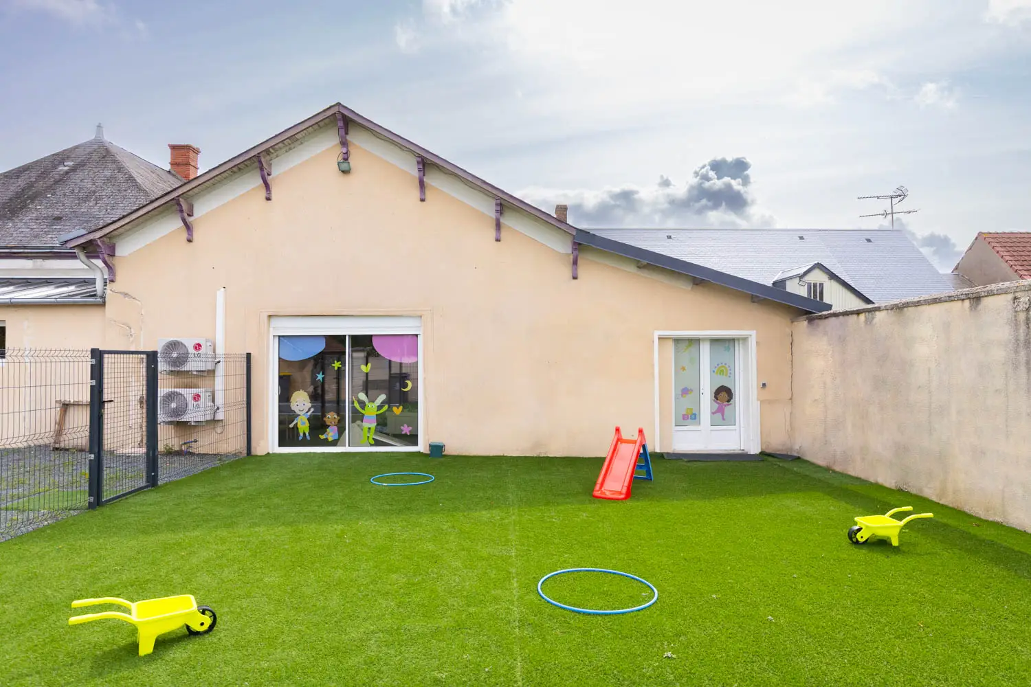 Jardin extérieur engazonné de la micro-crèche de Montierchaume avec toboggan