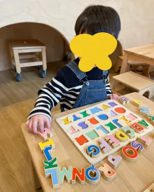 Enfant jouant avec un puzzle alphabet d'éveil cognitif à la crèche Les Explorateurs de Montreuil