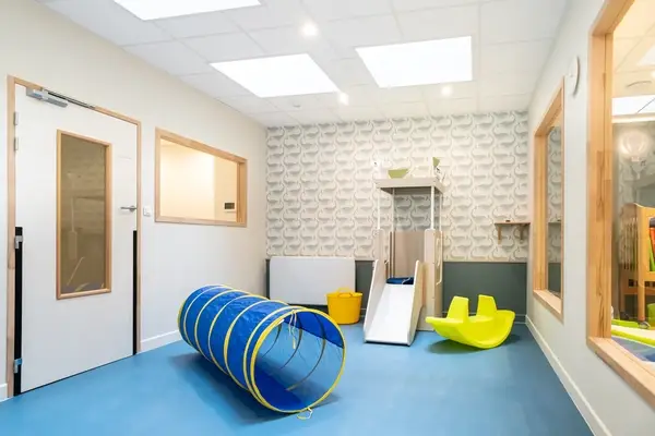 Salle de motricité avec tunnel et toboggan à la micro-crèche Saint-Ambroise
