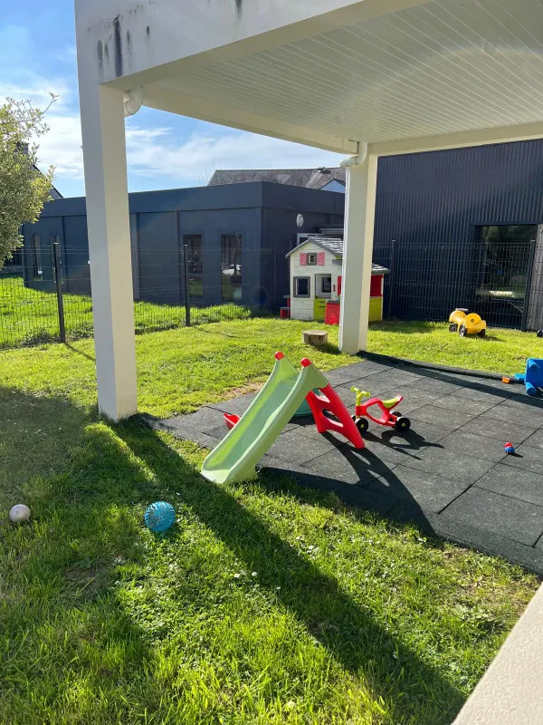 Jardin extérieur avec toboggan et cabane à la micro-crèche Les Chérubins Malins de La Mézière