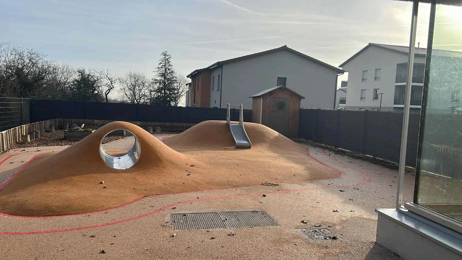 Cour extérieure avec toboggan et tunnel à la crèche À Petits Pas d'Orliénas