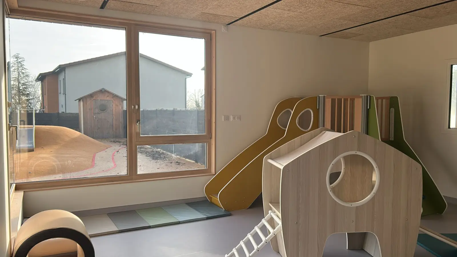 Espace de motricité avec toboggan et mur d'escalade à la crèche À Petits Pas d'Orliénas