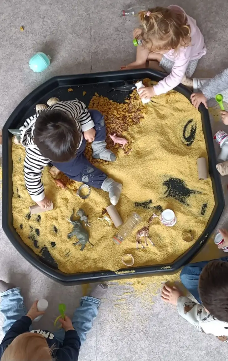 Enfants explorant un bac sensoriel à la micro-crèche de Sannerville
